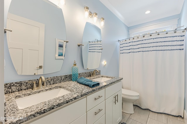 full bathroom featuring toilet, a shower with curtain, a sink, and double vanity