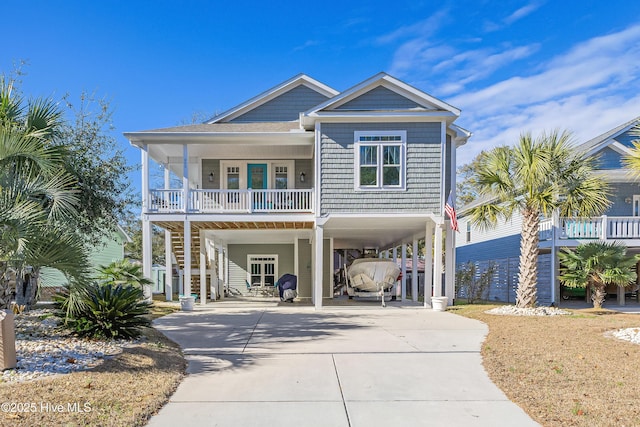 raised beach house with a carport, stairway, covered porch, and driveway