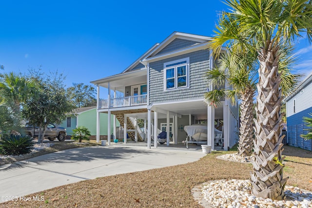 rear view of property featuring covered porch, concrete driveway, stairs, and a carport