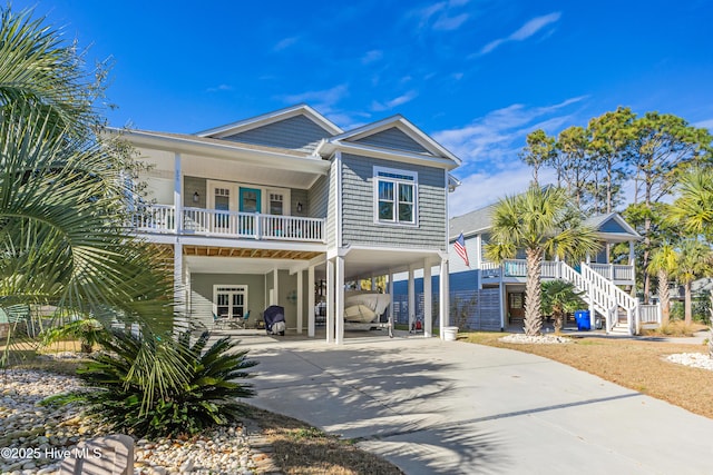 beach home with driveway, a carport, stairs, and covered porch