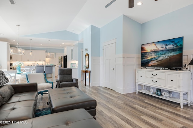 living room featuring recessed lighting, light wood finished floors, a wainscoted wall, vaulted ceiling, and ceiling fan