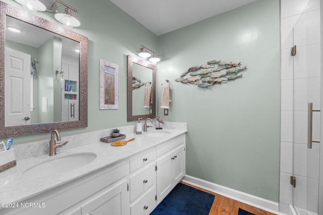 bathroom with a shower with shower door, hardwood / wood-style flooring, and vanity