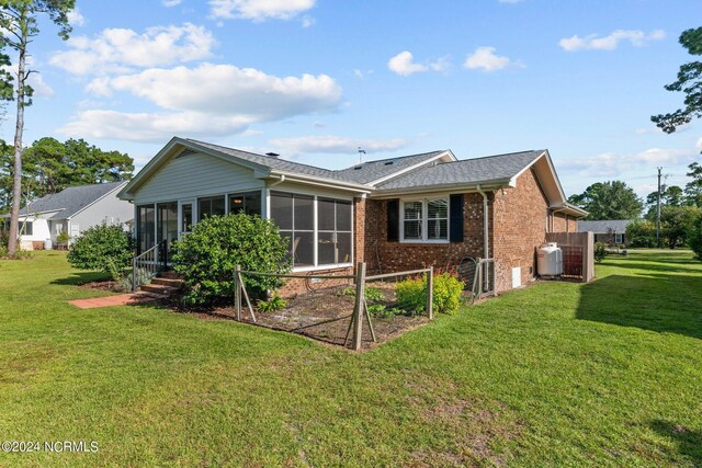 rear view of property featuring a sunroom and a yard