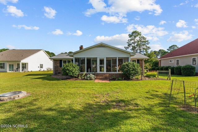 rear view of property featuring a yard and a sunroom