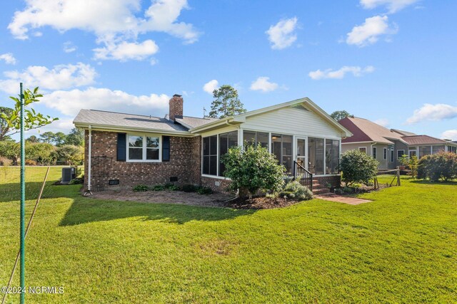 rear view of property with a sunroom, a lawn, and central AC