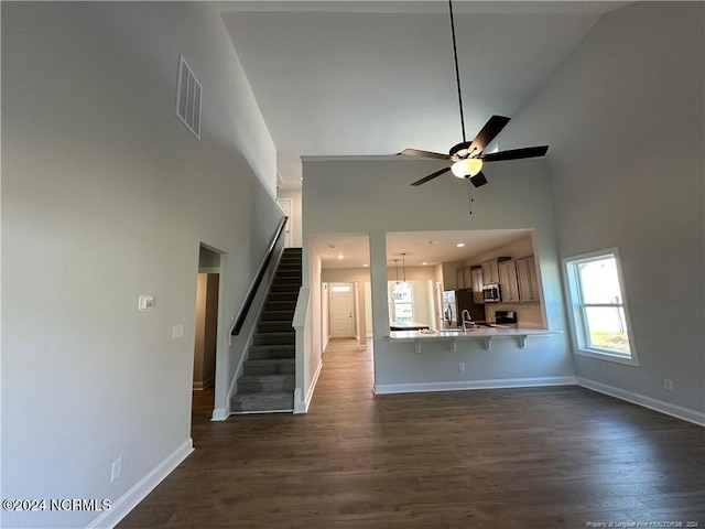 unfurnished living room with high vaulted ceiling, ceiling fan, and dark hardwood / wood-style flooring