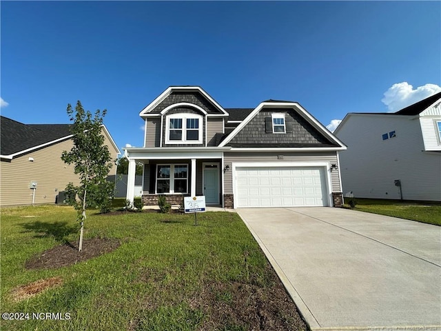 craftsman-style home with a garage, covered porch, and a front yard