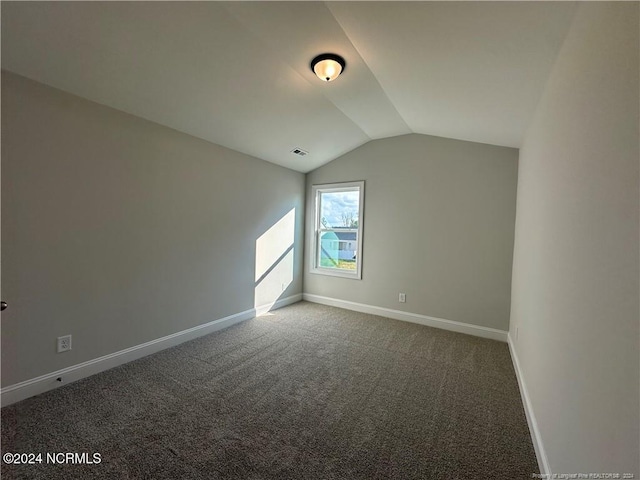 additional living space featuring dark carpet and vaulted ceiling