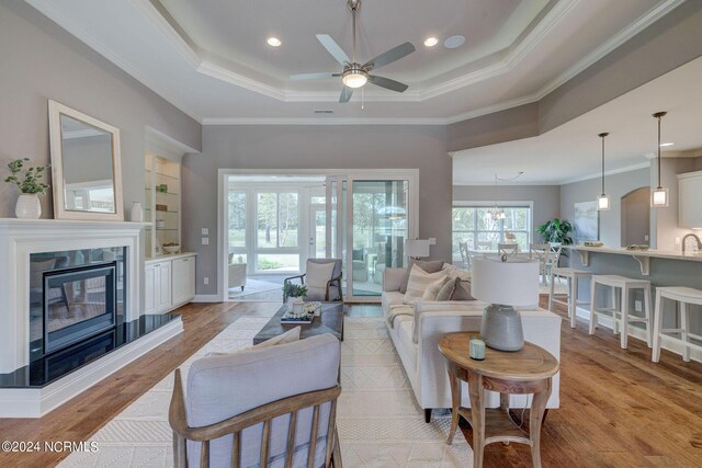 8711 Compass Pointe W Wynd Wynd NE, Leland, NC 28451 - living area with ornamental molding, light wood finished floors, a ceiling fan, and a tray ceiling