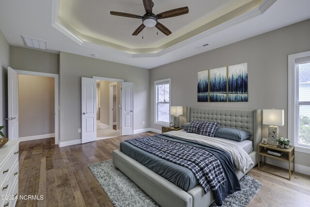 8711 Compass Pointe W Wynd Wynd NE, Leland, NC 28451 - bedroom featuring visible vents, wood finished floors, a tray ceiling, and multiple windows