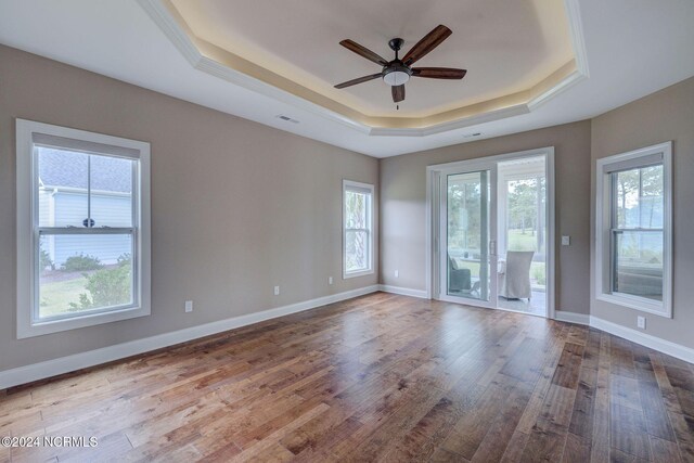 8711 Compass Pointe W Wynd Wynd NE, Leland, NC 28451 - empty room featuring visible vents, wood finished floors, baseboards, a tray ceiling, and a ceiling fan
