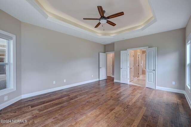 8711 Compass Pointe W Wynd Wynd NE, Leland, NC 28451 - unfurnished bedroom with baseboards, a raised ceiling, ceiling fan, and wood finished floors