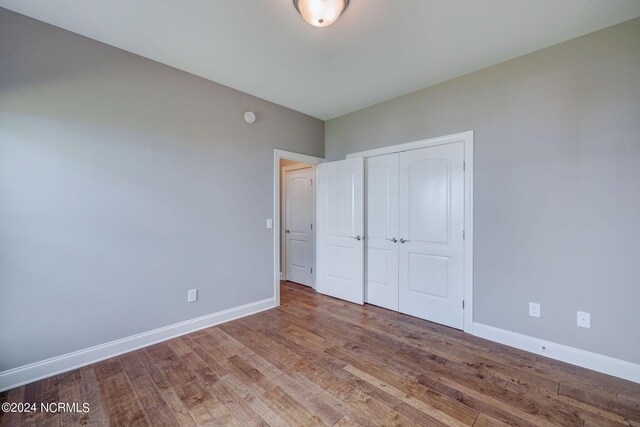 8711 Compass Pointe W Wynd Wynd NE, Leland, NC 28451 - unfurnished bedroom featuring baseboards, wood finished floors, and a closet