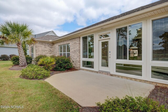 8711 Compass Pointe W Wynd Wynd NE, Leland, NC 28451 - rear view of house with a lawn, a patio, and brick siding