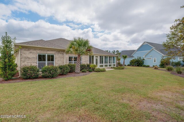 8711 Compass Pointe W Wynd Wynd NE, Leland, NC 28451 - rear view of house with a lawn, roof with shingles, brick siding, and a sunroom