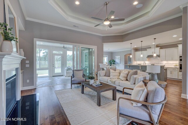 8711 Compass Pointe W Wynd Wynd NE, Leland, NC 28451 - living area with ceiling fan, ornamental molding, a tray ceiling, and light wood-style flooring