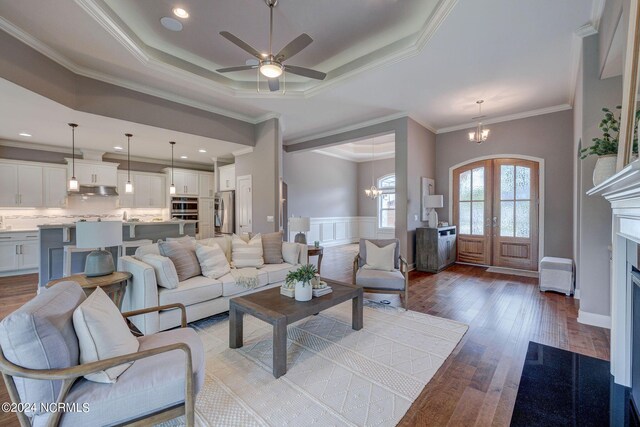 8711 Compass Pointe W Wynd Wynd NE, Leland, NC 28451 - living area featuring crown molding, dark wood-style flooring, wainscoting, a raised ceiling, and ceiling fan with notable chandelier