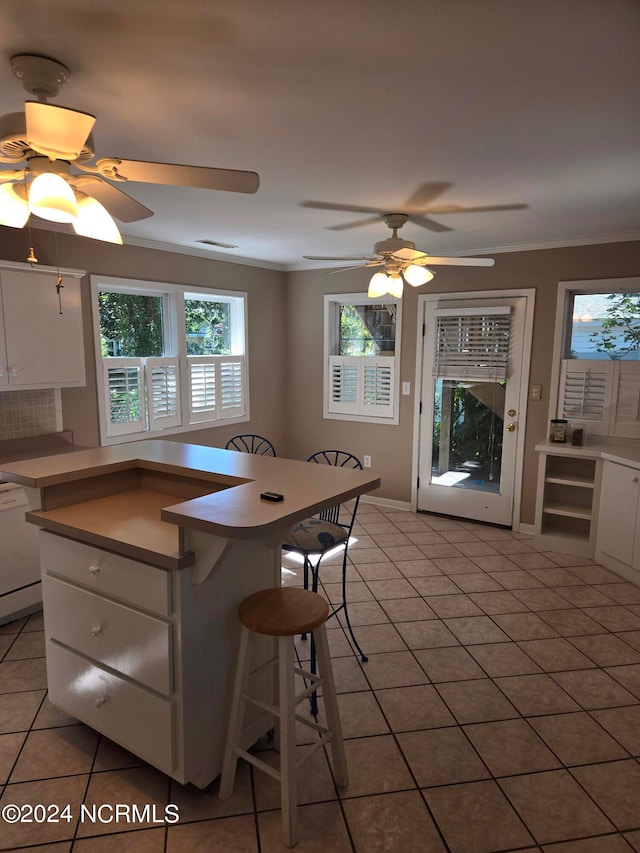 kitchen with ceiling fan, white dishwasher, light tile patterned flooring, white cabinetry, and crown molding