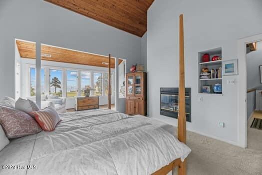 bedroom featuring carpet floors, wooden ceiling, and high vaulted ceiling