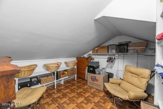 bonus room with dark parquet flooring and vaulted ceiling