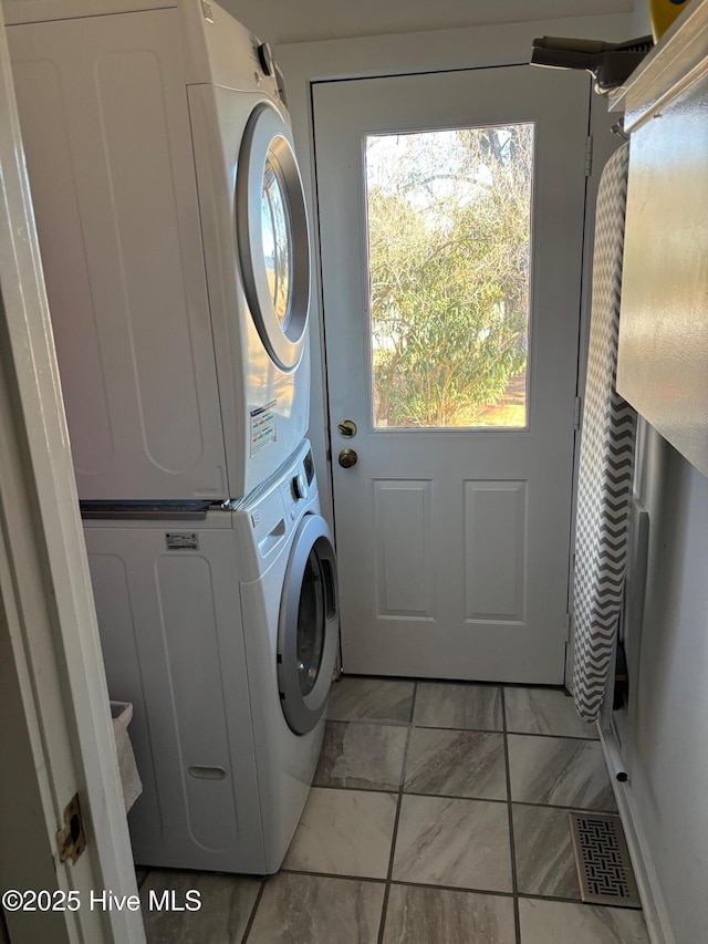 clothes washing area with light tile patterned floors and stacked washer / drying machine