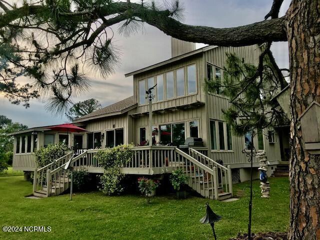 back of property featuring a deck and a lawn