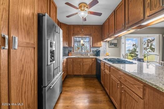 kitchen featuring dark wood-type flooring, sink, ceiling fan, appliances with stainless steel finishes, and light stone counters