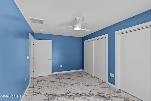 unfurnished bedroom featuring ceiling fan and multiple closets