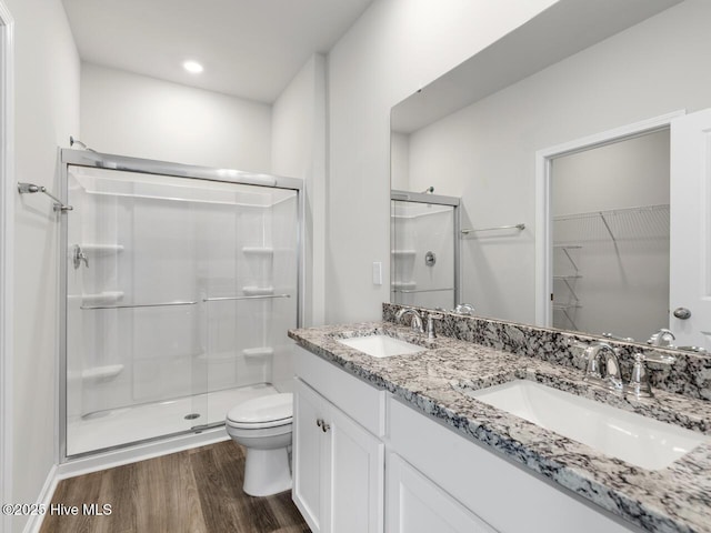 full bathroom featuring a stall shower, a sink, and wood finished floors