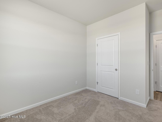 unfurnished bedroom featuring light carpet and baseboards