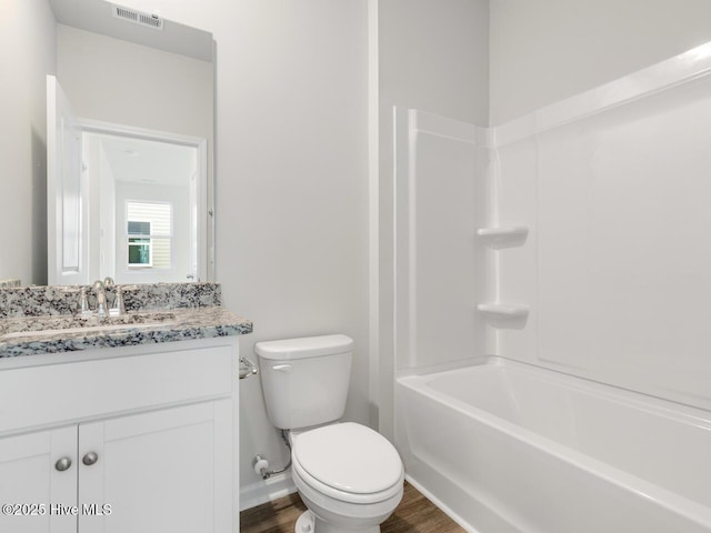 full bath with visible vents, bathing tub / shower combination, toilet, wood finished floors, and vanity