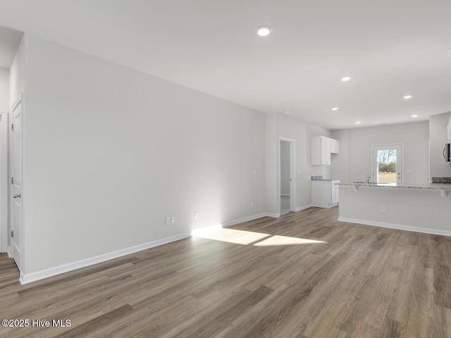 unfurnished living room with light wood-type flooring, baseboards, and recessed lighting