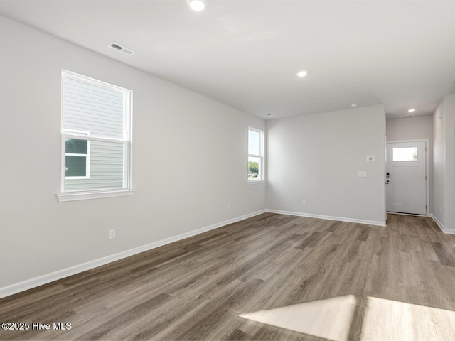 unfurnished room with light wood finished floors, plenty of natural light, visible vents, and baseboards