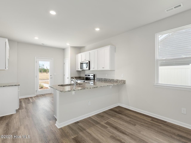 kitchen featuring stainless steel appliances, a peninsula, visible vents, white cabinets, and light stone countertops