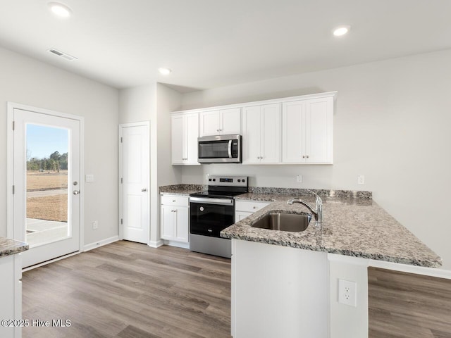 kitchen with a peninsula, a sink, visible vents, white cabinets, and appliances with stainless steel finishes