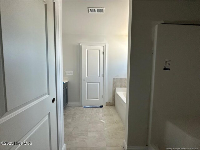 bathroom with a bathing tub, tile patterned flooring, and vanity