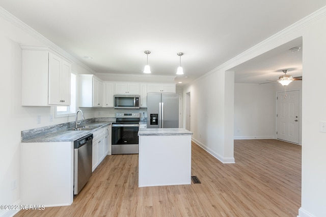 kitchen with pendant lighting, light wood-type flooring, white cabinetry, a kitchen island, and appliances with stainless steel finishes