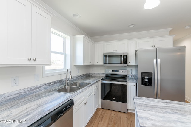 kitchen with white cabinets, ornamental molding, sink, light hardwood / wood-style flooring, and stainless steel appliances