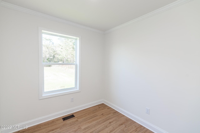 spare room with a healthy amount of sunlight, ornamental molding, and light hardwood / wood-style flooring