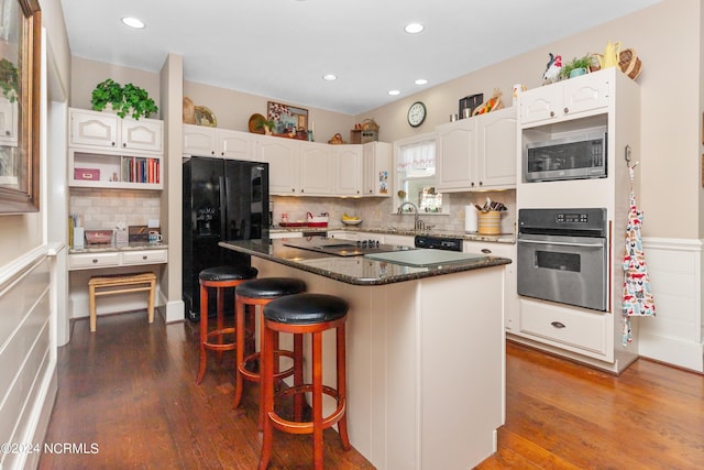 kitchen featuring white cabinets, a breakfast bar area, a kitchen island, and black appliances