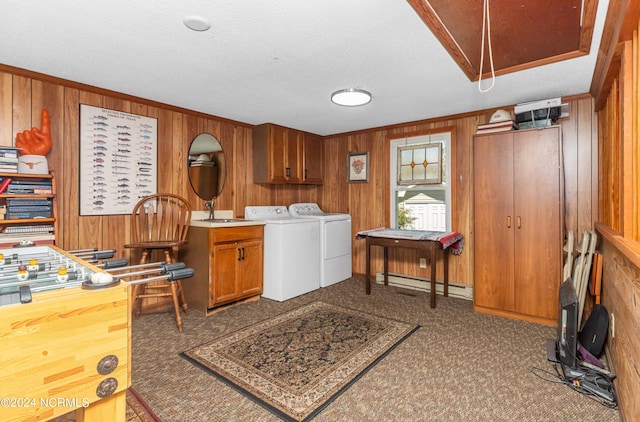 laundry area featuring baseboard heating, cabinets, washer and dryer, dark carpet, and wood walls