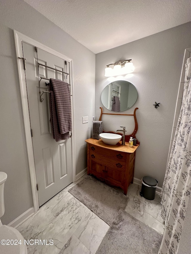 bathroom with walk in shower, vanity, toilet, and a textured ceiling