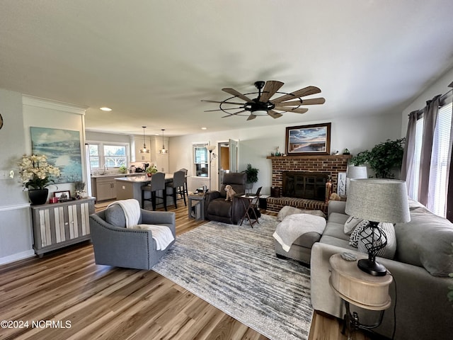 living room with plenty of natural light, hardwood / wood-style floors, and a brick fireplace