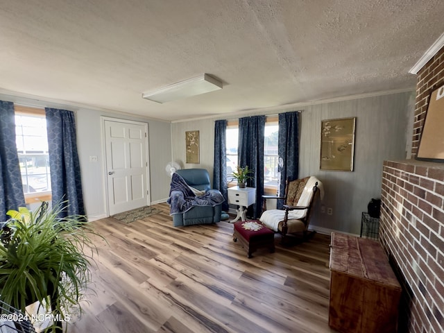 sitting room with crown molding, wood-type flooring, and a textured ceiling