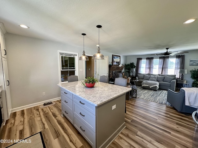 kitchen with white cabinetry, decorative light fixtures, light hardwood / wood-style flooring, and a kitchen island