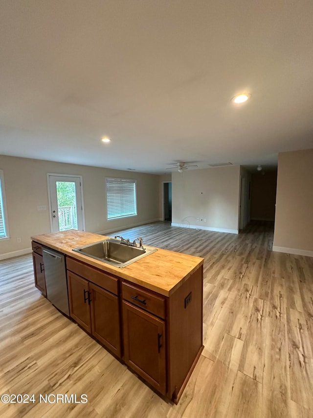 kitchen with a kitchen island with sink, wooden counters, sink, light hardwood / wood-style floors, and dishwasher