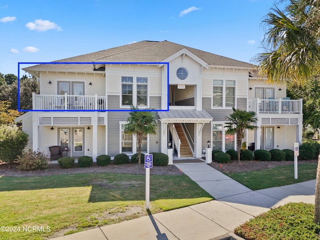 view of front of property with a balcony and a front lawn