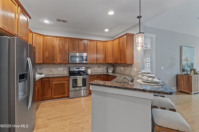 2537 St James Dr SE Unit 303, Southport, NC 28461 - kitchen featuring appliances with stainless steel finishes, a peninsula, a kitchen breakfast bar, dark stone countertops, and a sink