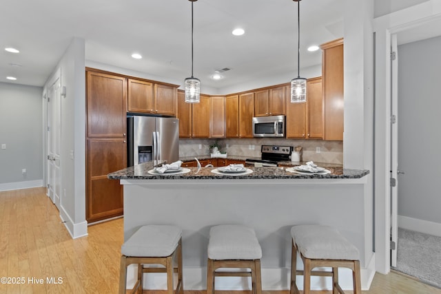 2537 St James Dr SE Unit 303, Southport, NC 28461 - kitchen with appliances with stainless steel finishes, dark stone counters, a kitchen bar, a peninsula, and recessed lighting