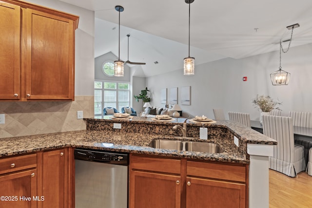 2537 St James Dr SE Unit 303, Southport, NC 28461 - kitchen featuring stainless steel dishwasher, a sink, brown cabinetry, dark stone counters, and lofted ceiling